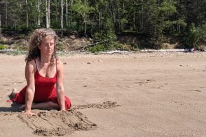 Femme en rouge pratiquant du Yoga therapeutique sur la plage | yoga en ligne et cours de yoga - France, Suisse, Belgique, Québec, Canada | Liance